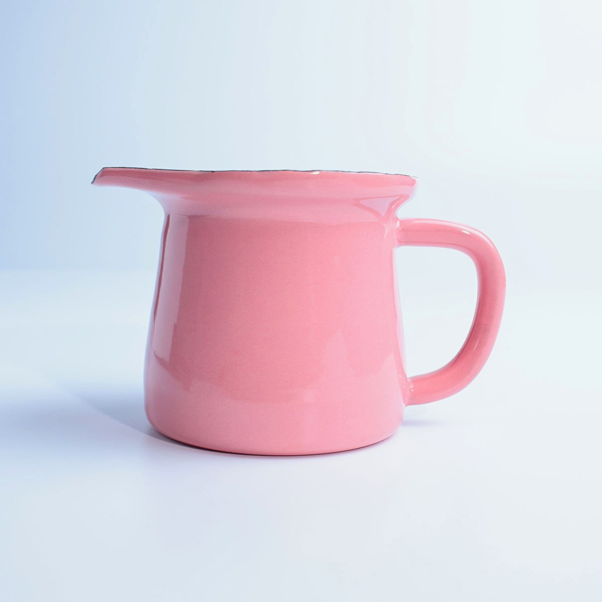 Beyaz zemin üzerinde, kulplu ve ağızlı, parlak pembe renkte emaye sosluk.
